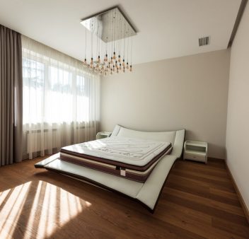 interior of modern bedroom with bed and light bulbs on ceiling