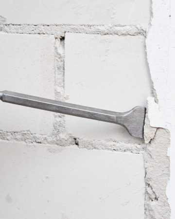 Man with demolition hammer remove stucco from wall. Renovation concept